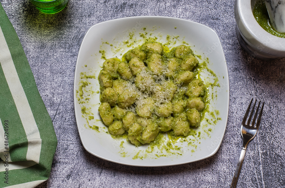 Potato gnocchi seasoned with pesto alla genovese. The potato gnocchi are homemade with organic potatoes. A typical traditional Italian food, healthy and nutritious.