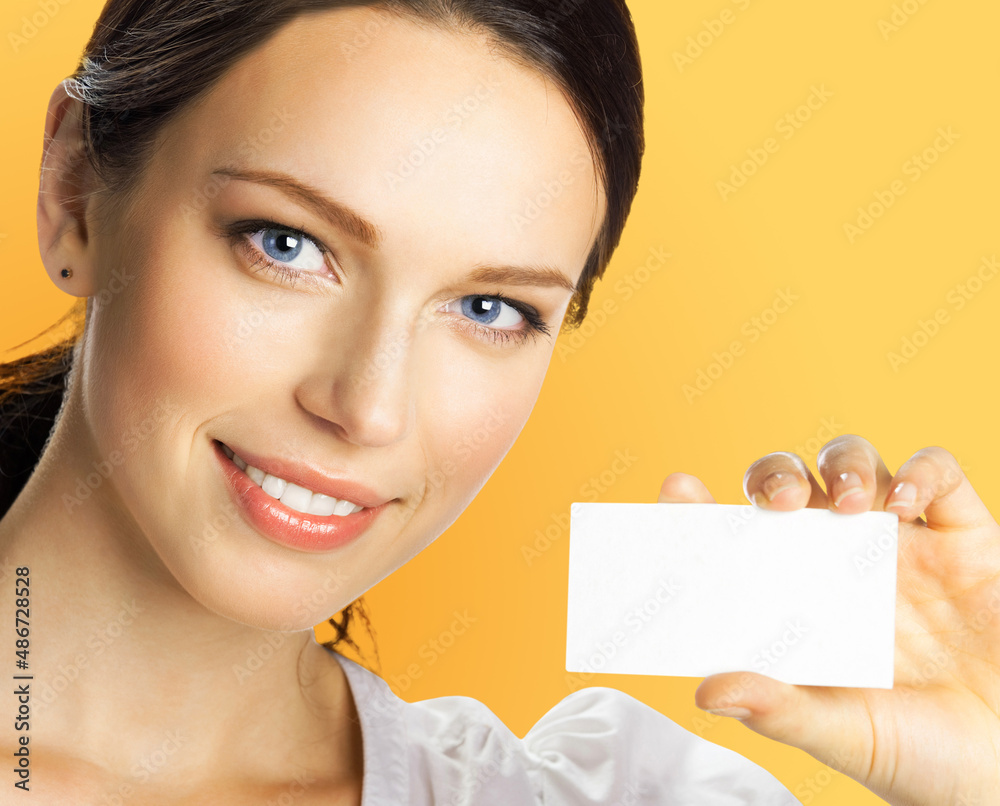 Closeup portrait of smiling businesswoman showing mockup empty businesscard or plastic credit card, with copy space for sign on orange yellow color background. Brunette business woman at studio image. Closeup portrait of smiling businesswoman showing mockup empty businesscard or plastic credit card, with copy space for sign on orange yellow color background. Brunette business woman at studio image.