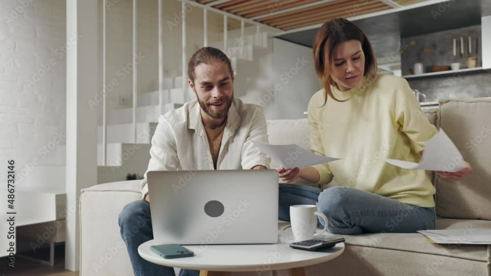 Married couple using laptop and calculating bills at home Married couple using laptop and calculating bills at home