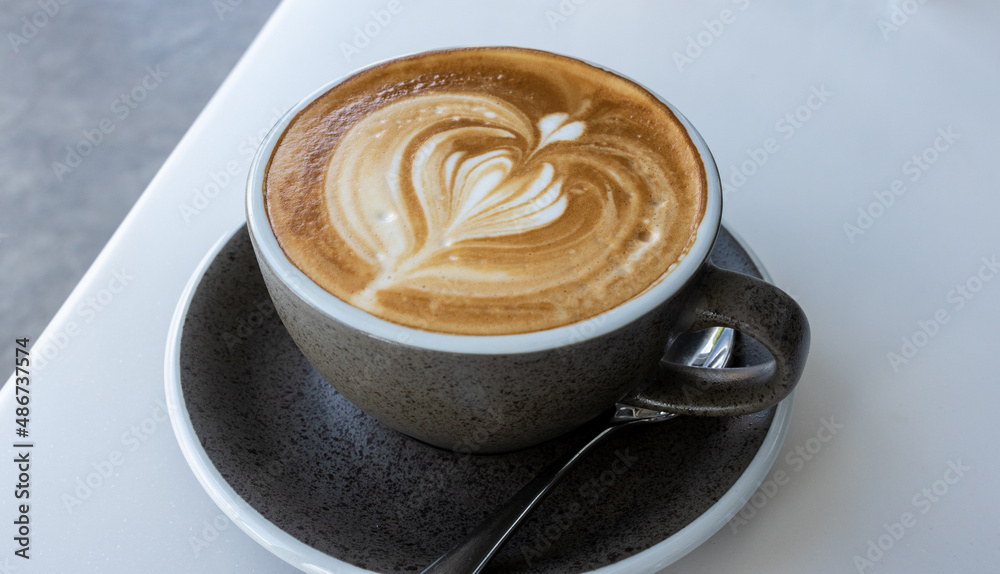 Hot latte With art milk froth in a coffee cup on a white table. Hot latte With art milk froth in a coffee cup on a white table.