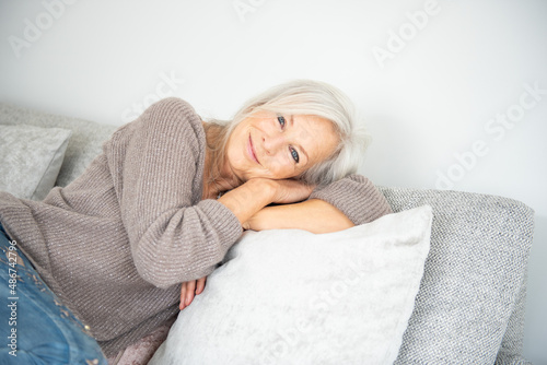 Fototapet bellissima donna sopra i 50 anni che si rilassa sul divano con sguardo dolce e a