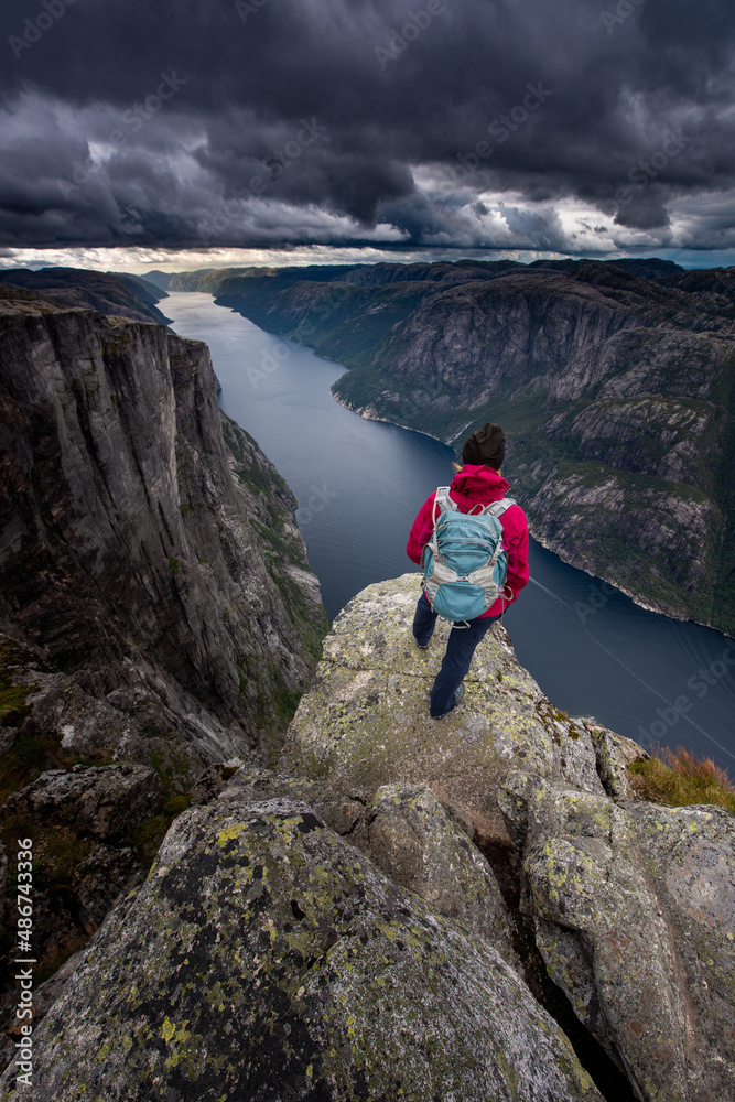 Eagle head viewpoint near Kjeragbolten Lysebotn Norway Woman stands by the edge of lysefjord