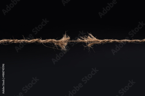 Frayed rope ready to break isolated on black background photo