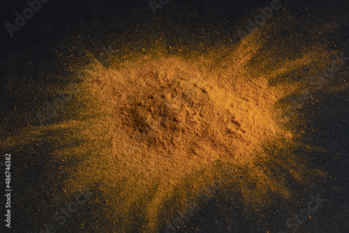 Turmeric powder on dark background, indian spice, healthy seasoning ingredient for vegan cuisine concept