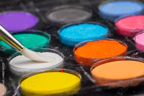 A set of colored paints with a brush in a box