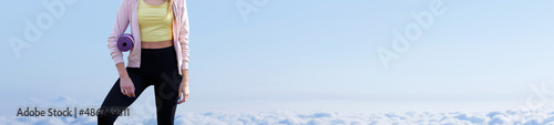 A young slim athletic girl in sportswear performs a set of exercises. Fitness and healthy lifestyle  against the background of clouds sky.