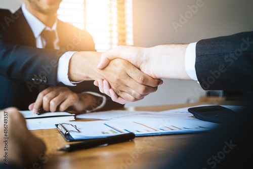 Above view hand of client and banker shaking hands  on the meeting table after business investment budget done