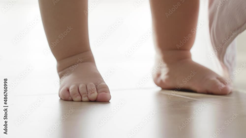 Close-Up Little Feet Standing On Warm Floor At Home, Baby Learning To Walk, Baby first steps Without Any Help. Toddler Exploring Home, Concept Newborn And Childhood, Slow Motion Close-Up Little Feet Standing On Warm Floor At Home, Baby Learning To Walk, Baby first steps Without Any Help. Toddler Exploring Home, Concept Newborn And Childhood, Slow Motion