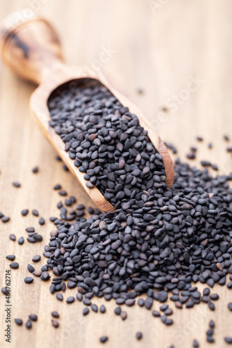 Bio natural black sesame seeds on wooden spoon.