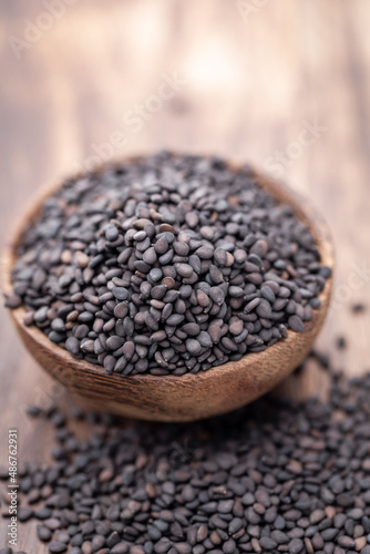 Bio natural black sesame seeds on wooden bowl.