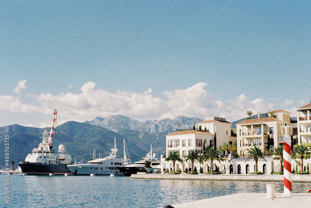 Expensive yachts on the pier in Porto with mountains in the background. Montenegro