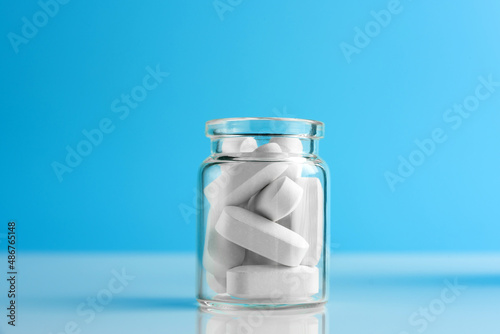 Konstfotografi Pills in a glass bottle on a blue background with copy space.