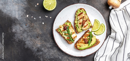 Grilled Halloumi cheese, avocado guacamole, arugula on roasted bread. banner, menu recipe place for text, top view