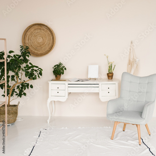 Stylish work area in the house. Scandinavian interior. White desk and armchair  large houseplant
