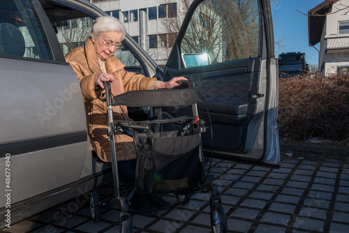 Senior woman with helping rollator getting out of car 
