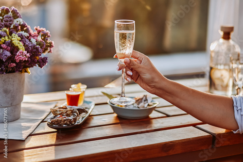 Woman eating fresh oysters and drinking chilled prosecco wine on the summer sunset. Seafood delicacies photo