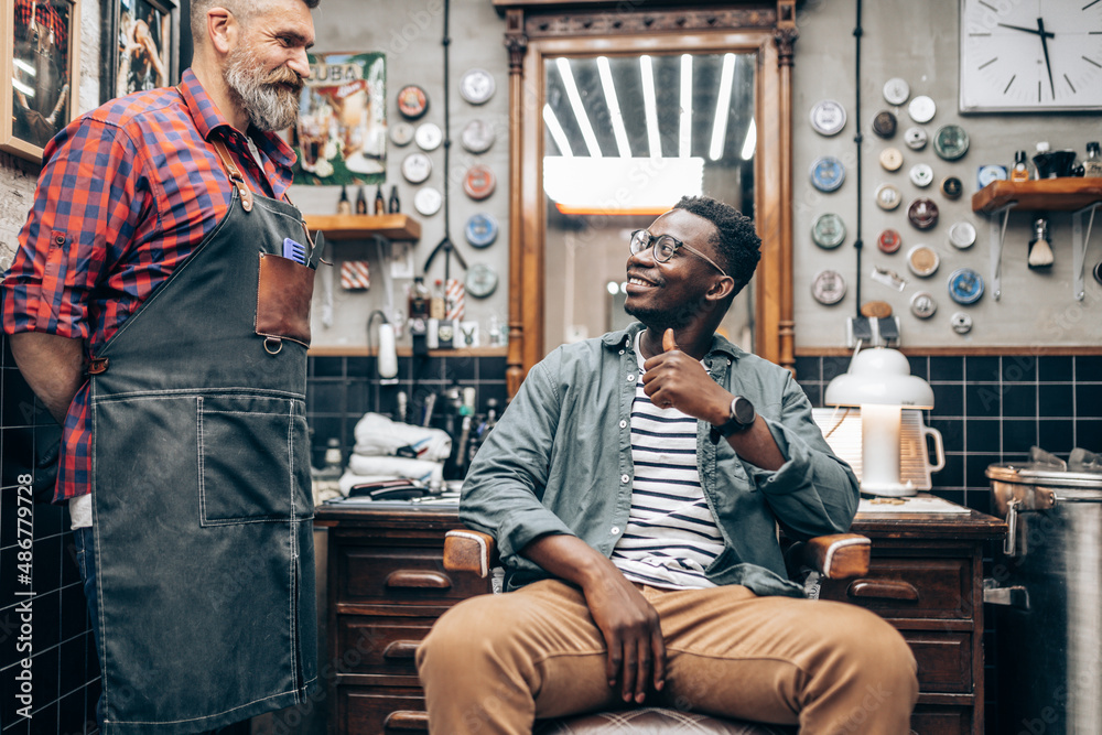 Young African American man smiling satisfied after treatment in barber shop.