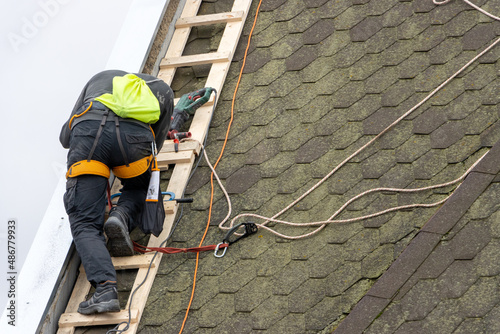 A man works on the roof repair, installs sheet metal on top of the gable wall photo