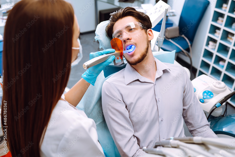 Man having a visit at the dentist's. Handsome patient sitting on chair at dentist office in dental clinic. Healthy teeth and medicine concept. Man having a visit at the dentist's. Handsome patient sitting on chair at dentist office in dental clinic. Healthy teeth and medicine concept.