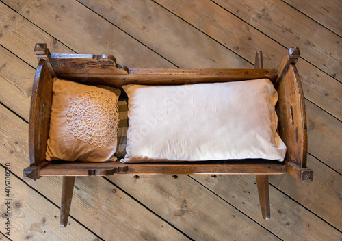 Old cradle with duvet and pillow on the wooden floor. photo