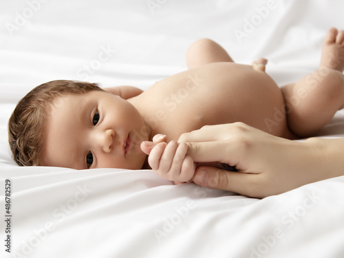 Mother holding head of baby In the safe hands. Mother's Care. Mom's Hand Stroking Sleeping Baby's Head During Daytime Sleep In Bed At Home. Mommy Caring For Her Infant baby While He Sleeps Peacefully