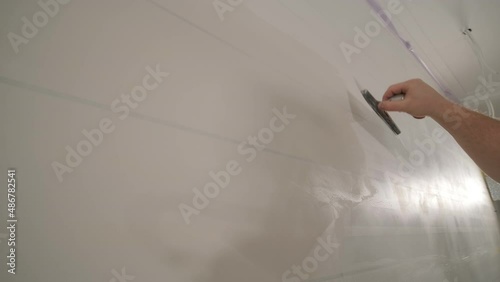 Man plastering the walls with finishing putty in room with putty spatula photo