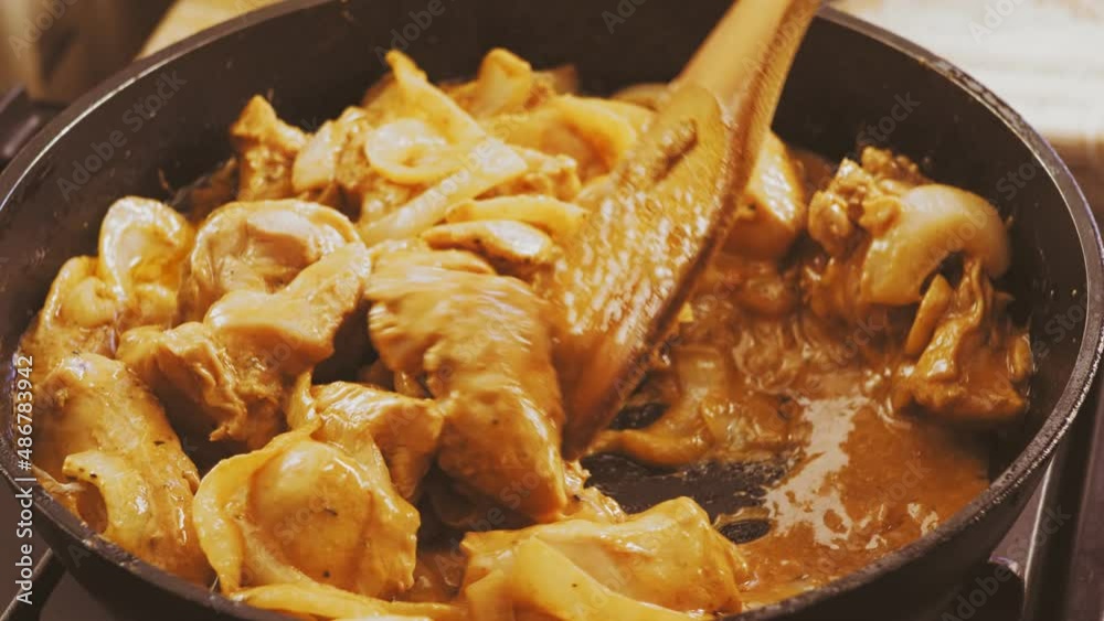 The chicken pieces in the marinade are mixed with a spatula in a pan. Medium plan The chicken pieces in the marinade are mixed with a spatula in a pan. Medium plan