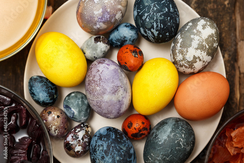 Dyed colored Easter Eggs with marble stone effect, colored with natural dye turmeric, onion husk, hibiscus flower tea on old tree background. 