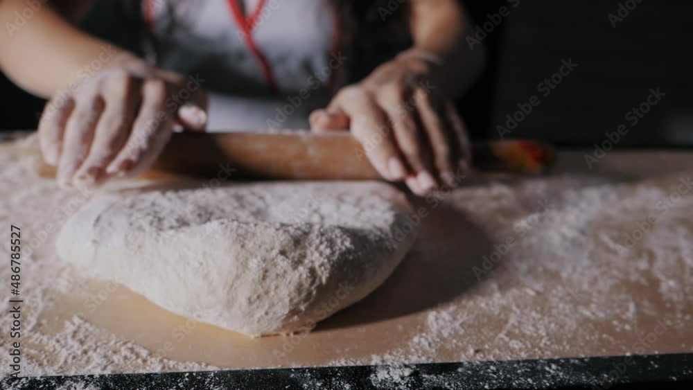 Female hands gently knead the dough with rolling pin, close-up in slow motion, the camera moves behind the hands Female hands gently knead the dough with rolling pin, close-up in slow motion, the camera moves behind the hands