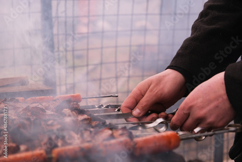 
a man roasts meat on a fire.
Close-up of hands and shish kebab.
Cooking pork neck on the grill. Roasted carrots. Fatty food, festive food of the CIS countries. May 1, labor day. Not vegan food.