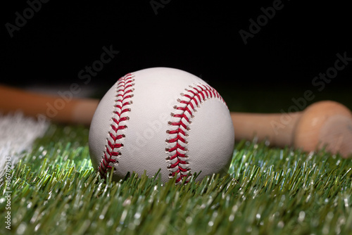 Baseball close up low angle with bat on grass field and black background photo