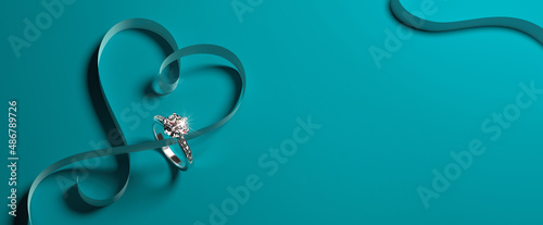 A white gold engagement ring with diamonds and a heart-shaped ribbon on a turquoise (tiffany blue) background. Romantic wedding jewelry background. 