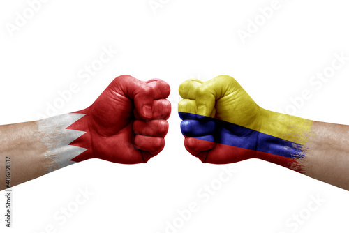 Two hands punch to each others on white background. Country flags painted fists, conflict crisis concept between bahrain and colombia