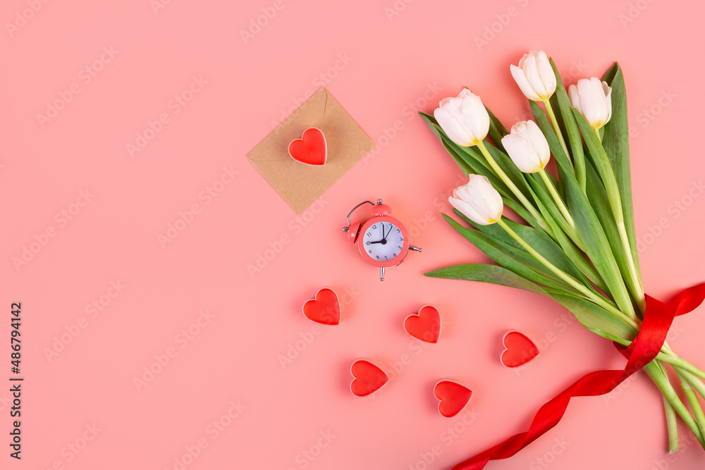 Bouquet of white tulips, hearts, envelope and a clock on an isolated pastel pink background. Time for love, decoration for women's day, mother's day, anniversary. Flatlay. Romantic date concept