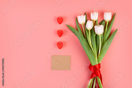 Fototapeta Naklejka Na Ścianę i Meble -  Bouquet of white tulips, hearts, envelope love letter on an isolated pastel pink background. Time for love, decoration for women's day, mother's day, anniversary. Flatlay. Romantic date concept