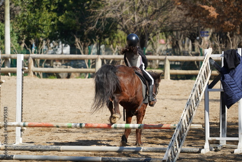 Young people  Junior  receiving riding training at a professional horse farm are practicing show jumping
