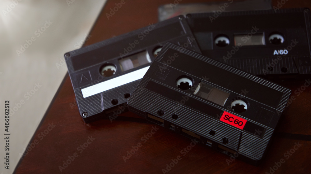 Obraz premium sobre una mesa oscura de madera reposan un montón de casetes clásicos con la mejor música de los 80´s y 90´s