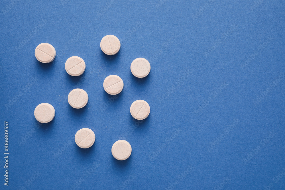 Many white pills on blue background Many white pills on blue background