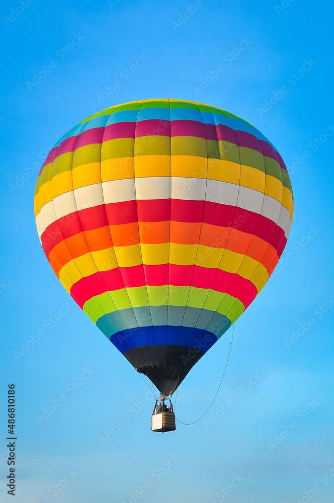 Naklejka premium Beautiful colorful hot air balloon flying on the clear blue sky background.