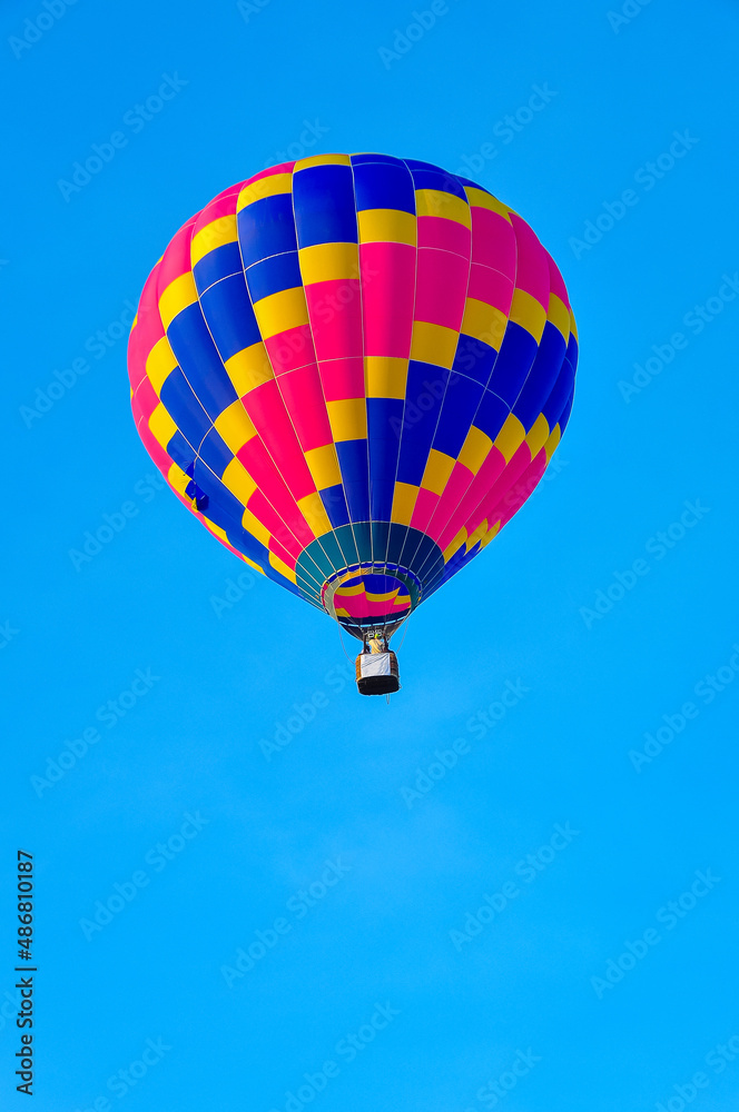Fototapeta premium Beautiful colorful hot air balloon flying on the clear blue sky background.