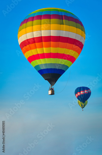Beautiful colorful hot air balloon flying on the clear blue sky background. © pomphotothailand