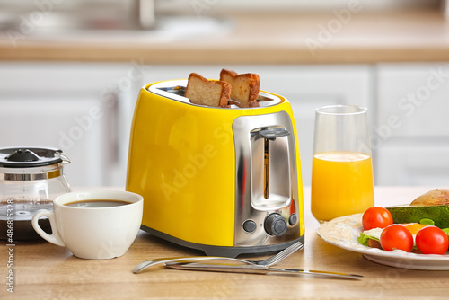 Yellow toaster with tasty food and drinks on counter in kitchen