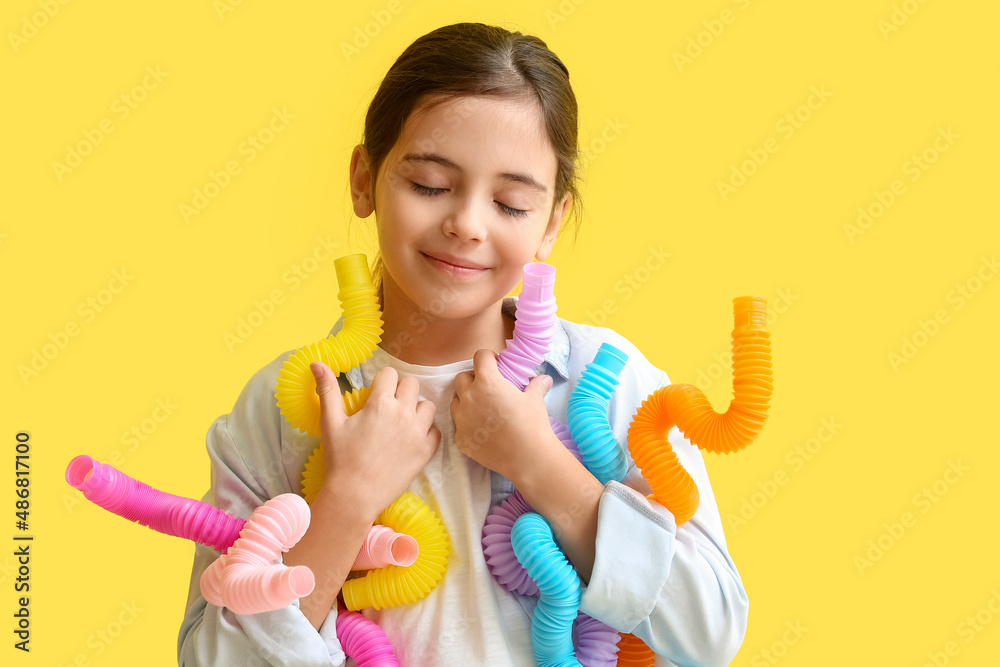 Little girl with Pop Tubes on yellow background Little girl with Pop Tubes on yellow background