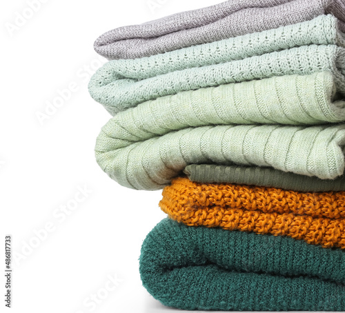Stack of knitted sweaters on white background, closeup