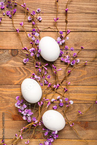 Composition with chicken eggs and beautiful flowers on wooden background