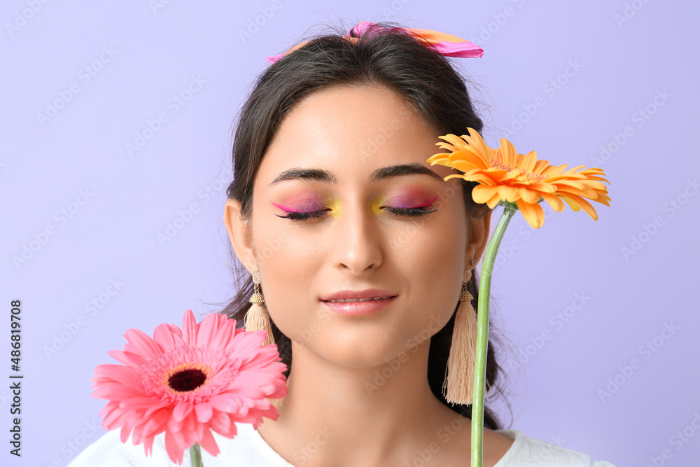 Young woman with creative makeup and gerbera flowers on violet background. International Women's Day Young woman with creative makeup and gerbera flowers on violet background. International Women's Day