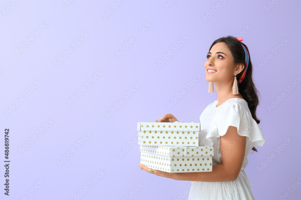 Woman with creative makeup holding gift boxes and looking up on violet background. International Women's Day Woman with creative makeup holding gift boxes and looking up on violet background. International Women's Day