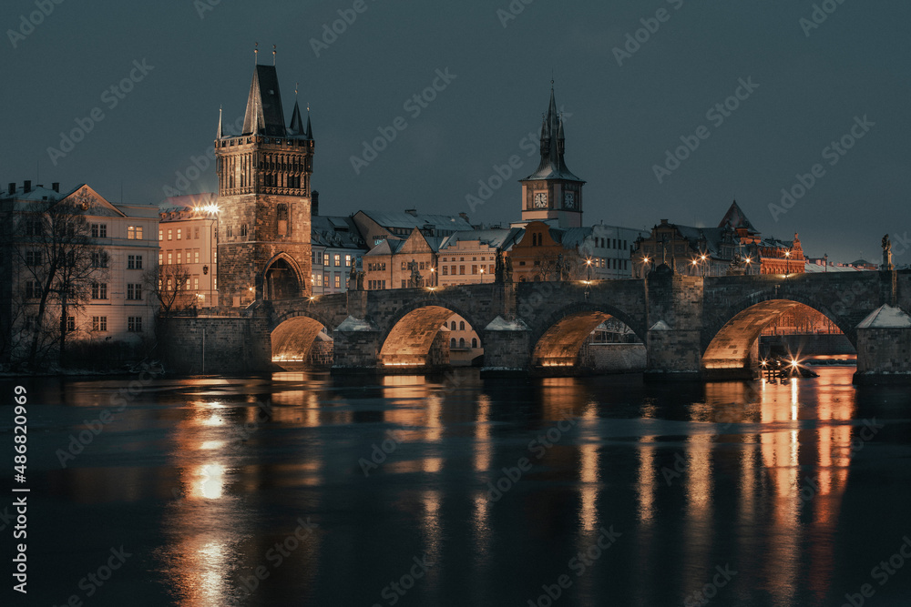 Snowy old stone Charles Bridge on the Vltava river in winter in the evening in the center of Prague