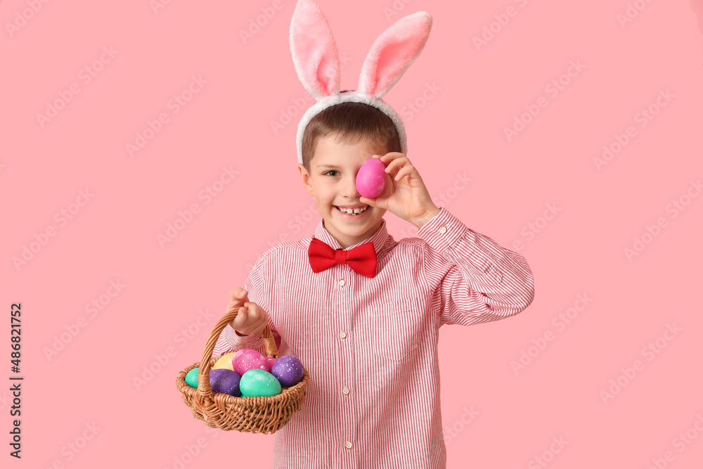 Funny little boy with bunny ears and Easter basket on pink background Funny little boy with bunny ears and Easter basket on pink background