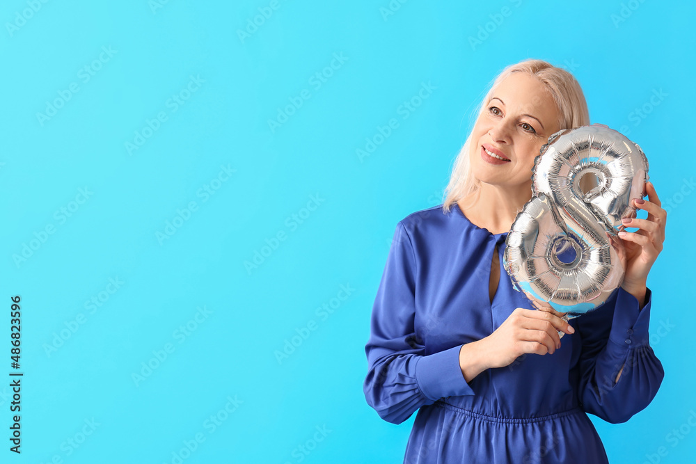 Mature woman with balloon in shape of figure 8 on blue background. International Women's Day Mature woman with balloon in shape of figure 8 on blue background. International Women's Day